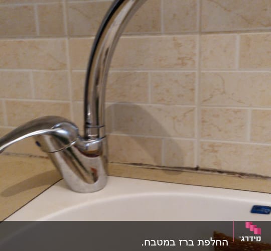 ברז מטבח כסוף מעל כיור לבן